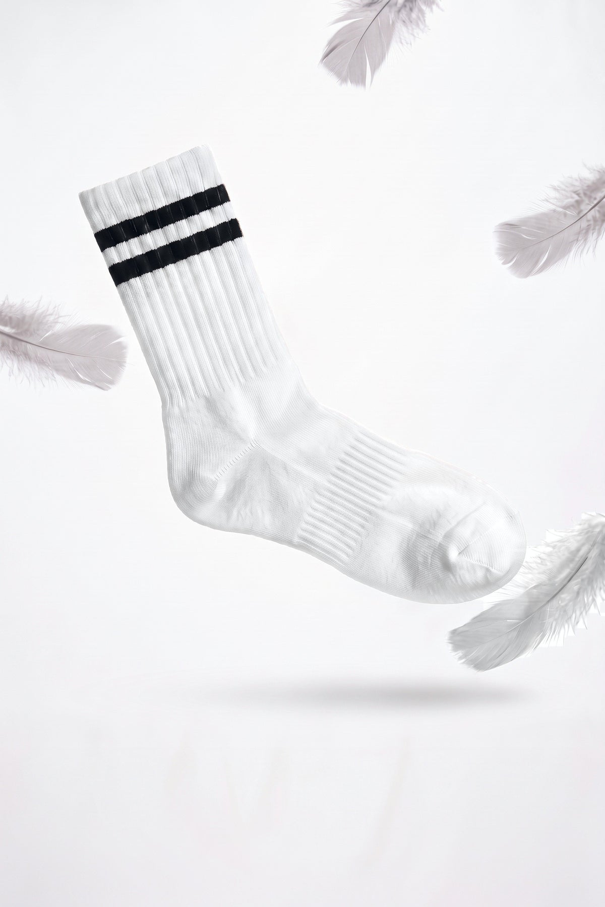 A white Panda Food bamboo crew sock drifting down among soft grey feathers